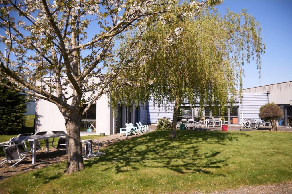 Le bâtiment de l’accueil de jour Arlequin à Vitré, sous un saule